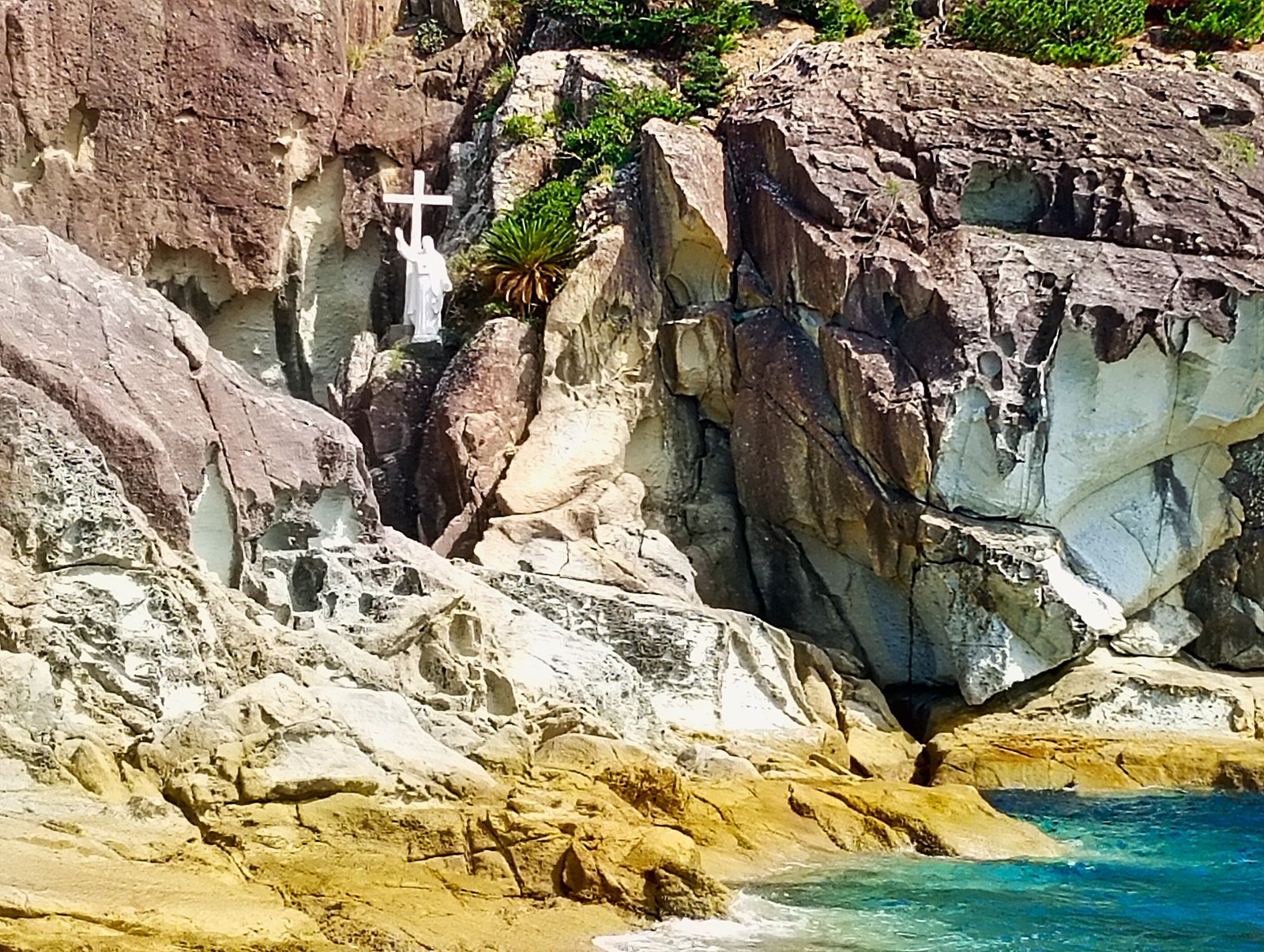 Rocky coastal cliffs with a cross and devotional statue